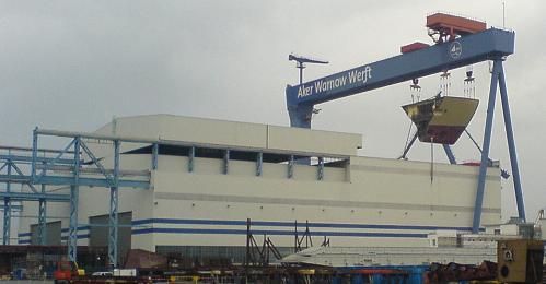 Anblick der Werfthalle Warnemünde - am Kran hängt das Segemnt einer neuen Fähre