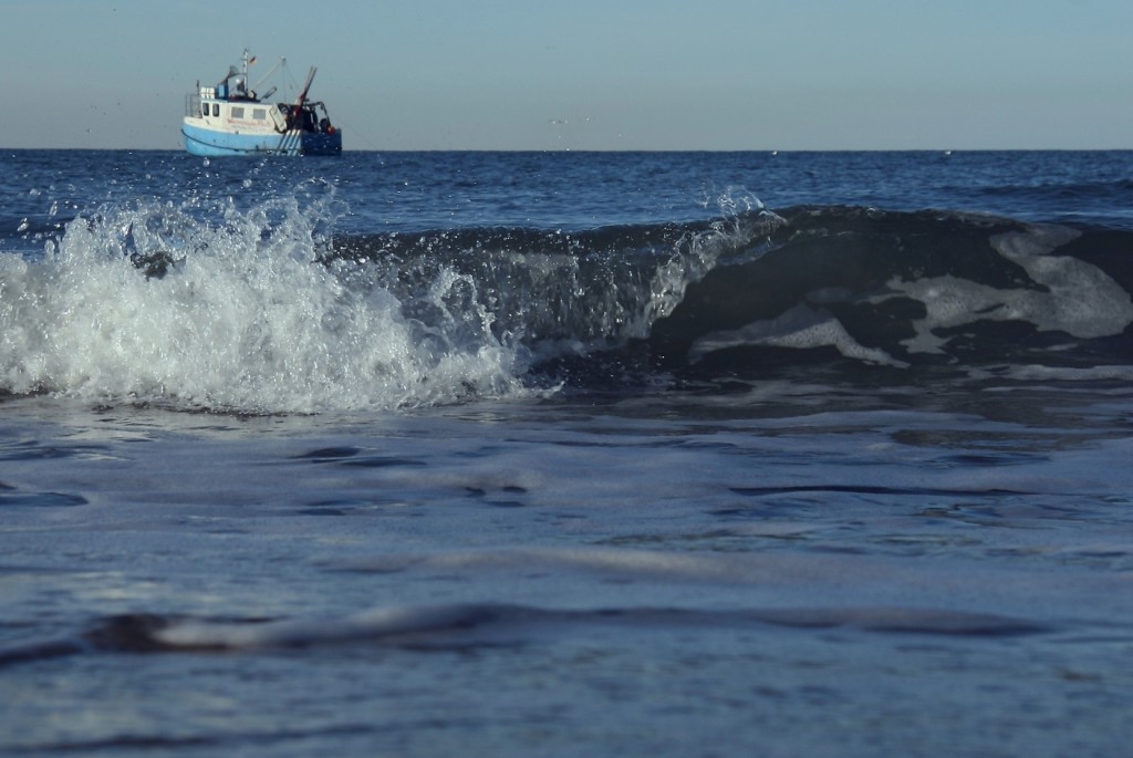 Kleine Welle bricht am Strand