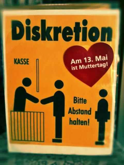 Schild: "Abstand halten" mit Muttertags-Werbung