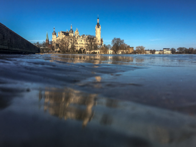 Das Schweriner Schloss spiegelt sich im dicken Eis auf der Schlossbucht.