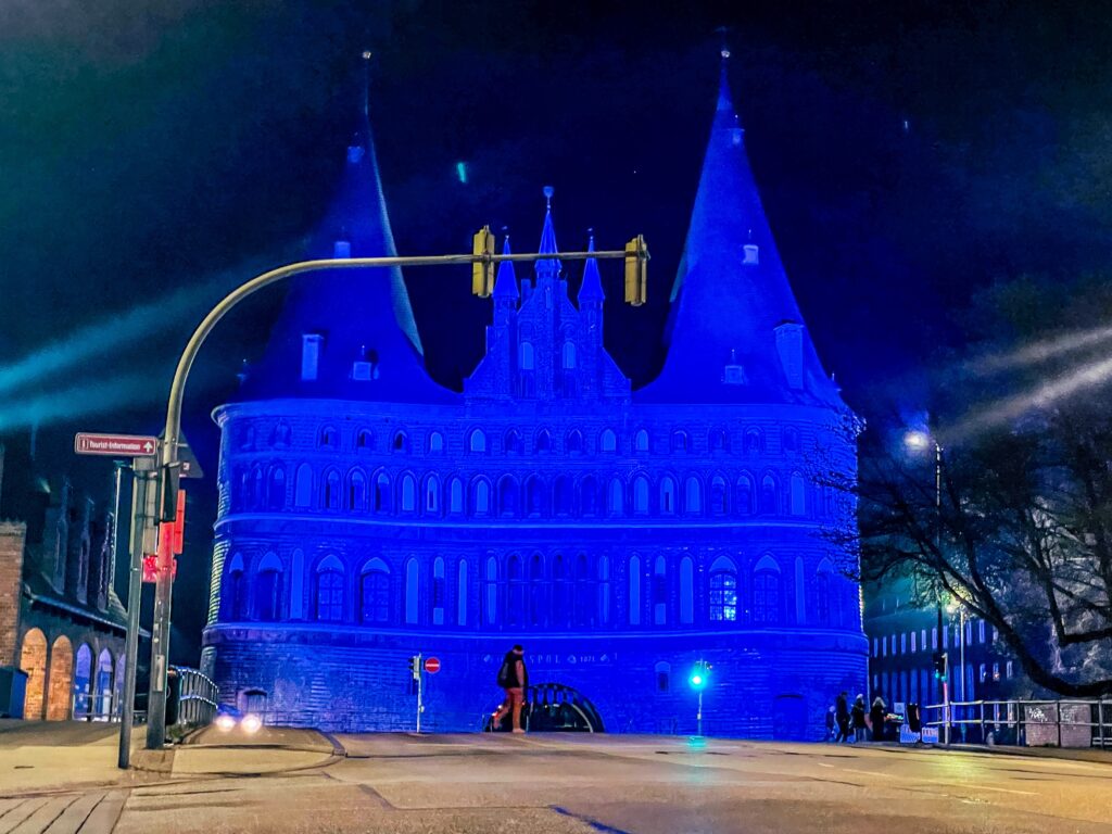 Das Holstentor in Lübeck nachts in leuchtendem Blau angestrahlt.